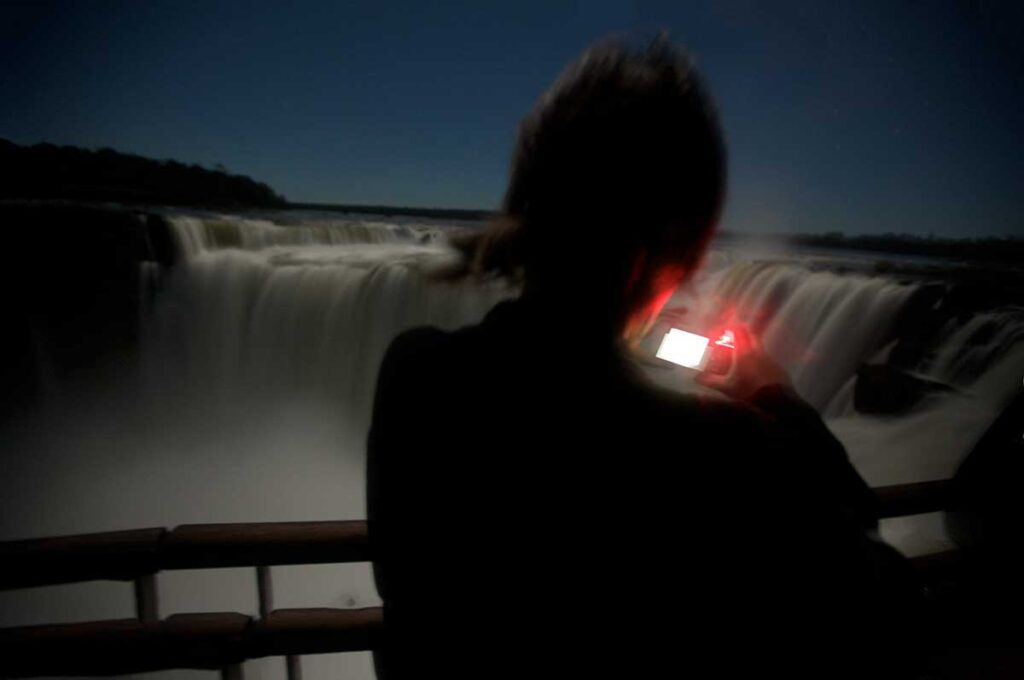Turistas en las Cataratas de Iguazú bajo la luz de la luna llena, turismo extractivista